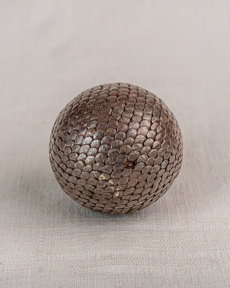 Early 20th-century antique French petanque ball with textured pattern, shown on light fabric; part of a set of five.