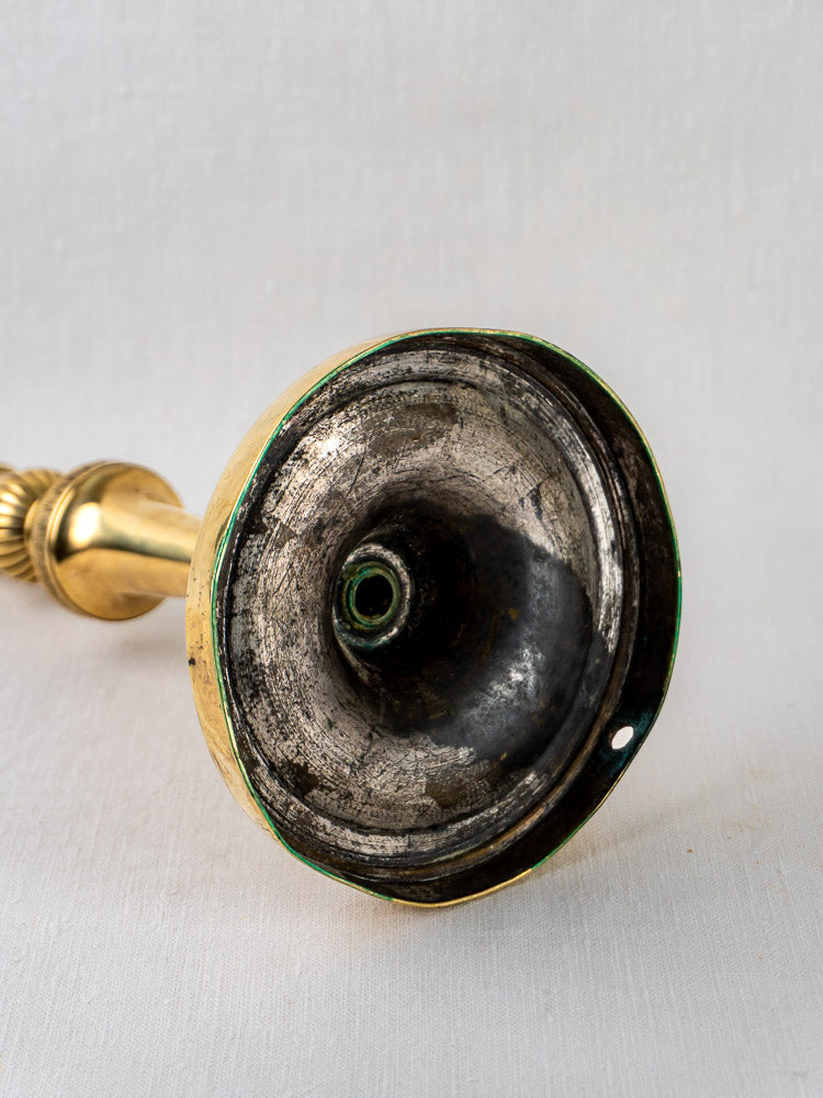 Underside of antique French brass candlestick, worn base with green rim and small edge hole.