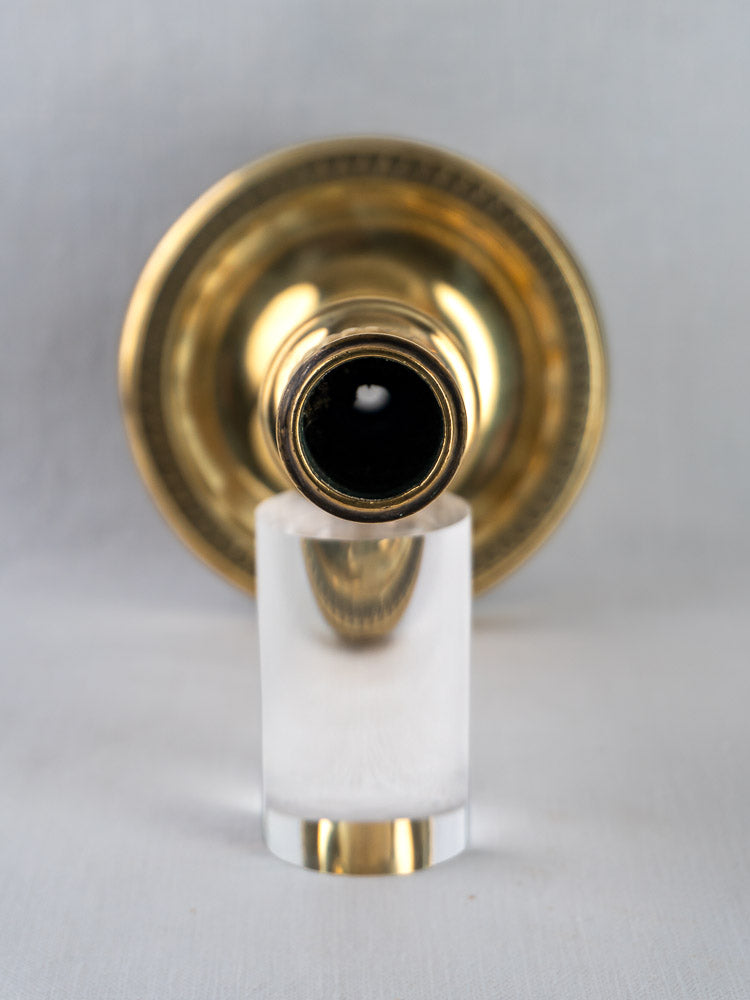 Antique French Empire palmette brass candlestick, top view on clear stand, plain background.