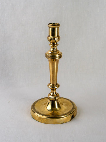Antique French Empire Palmette brass candlestick with ornate detailing on a round base.