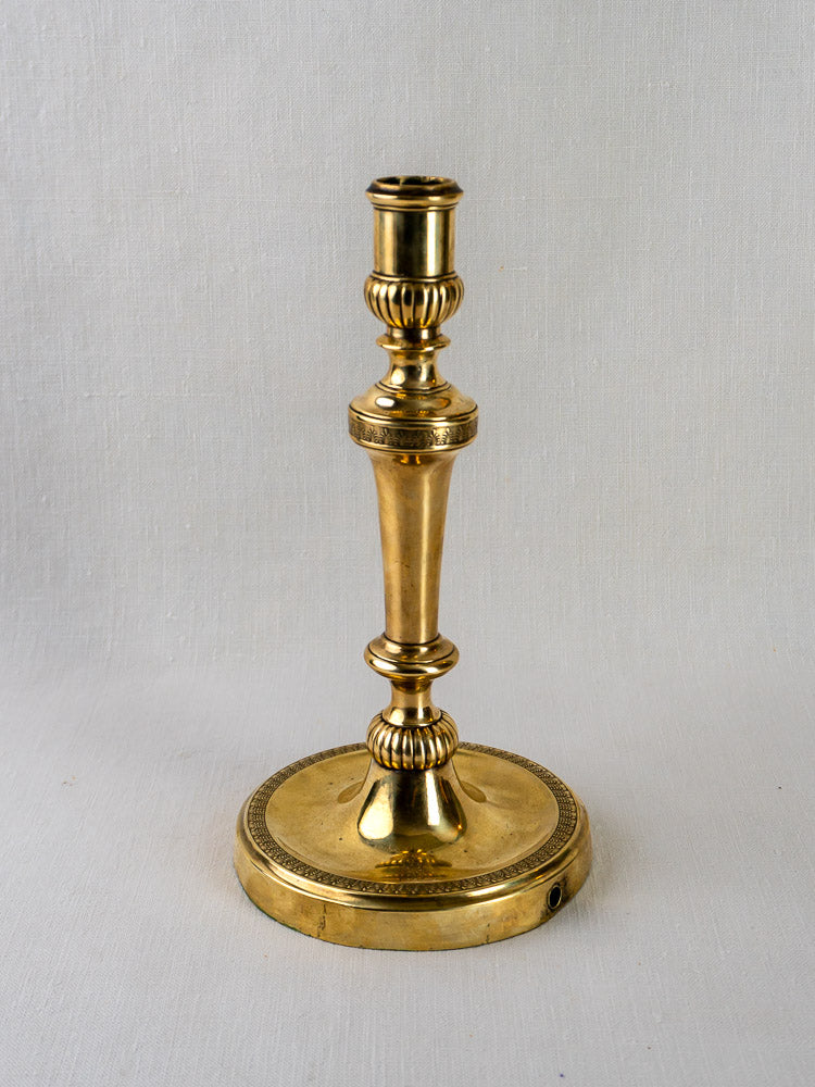 Antique French Empire Palmette brass candlestick with ornate detailing on a round base.