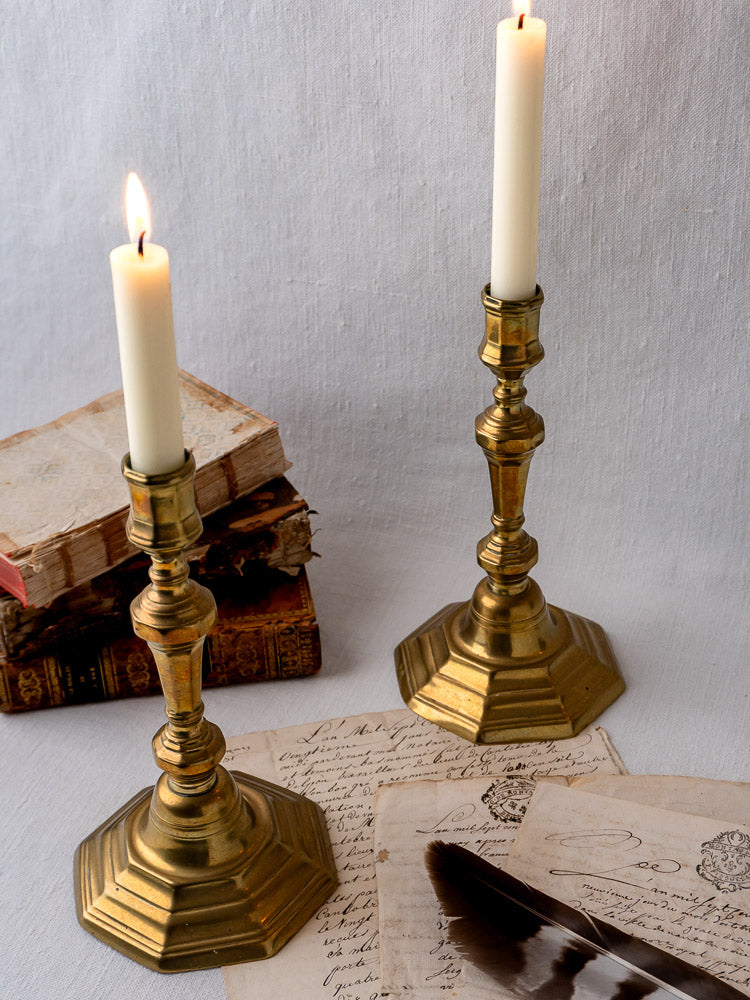 Louis XV antique French brass candlesticks with lit white candles, displayed on handwritten letters.