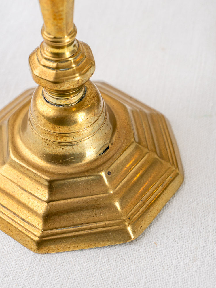 Louis XV antique French brass candlesticks with hexagonal bases and aged patina on white fabric.