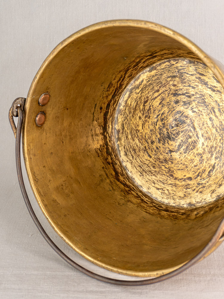 Antique French brass jam pan interior with metal handle, featuring scratches and timeworn golden patina.