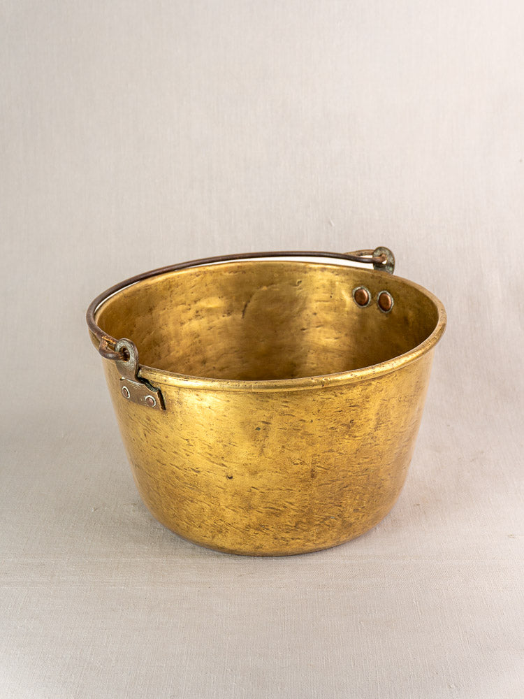 Antique French brass jam pan with handle, early 19th century, aged patina, displayed on light grey fabric.