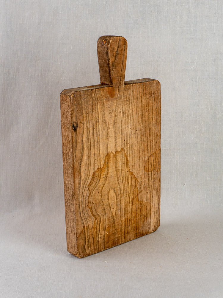 Antique French chestnut cutting board c. 1900 with rich wood grain and aged patina on light background.