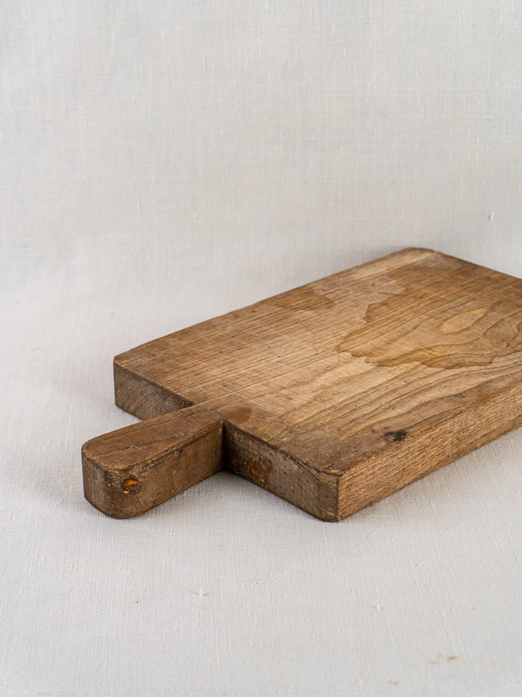 Antique French chestnut cutting board, circa 1900, with rectangular shape and short handle on textured surface.