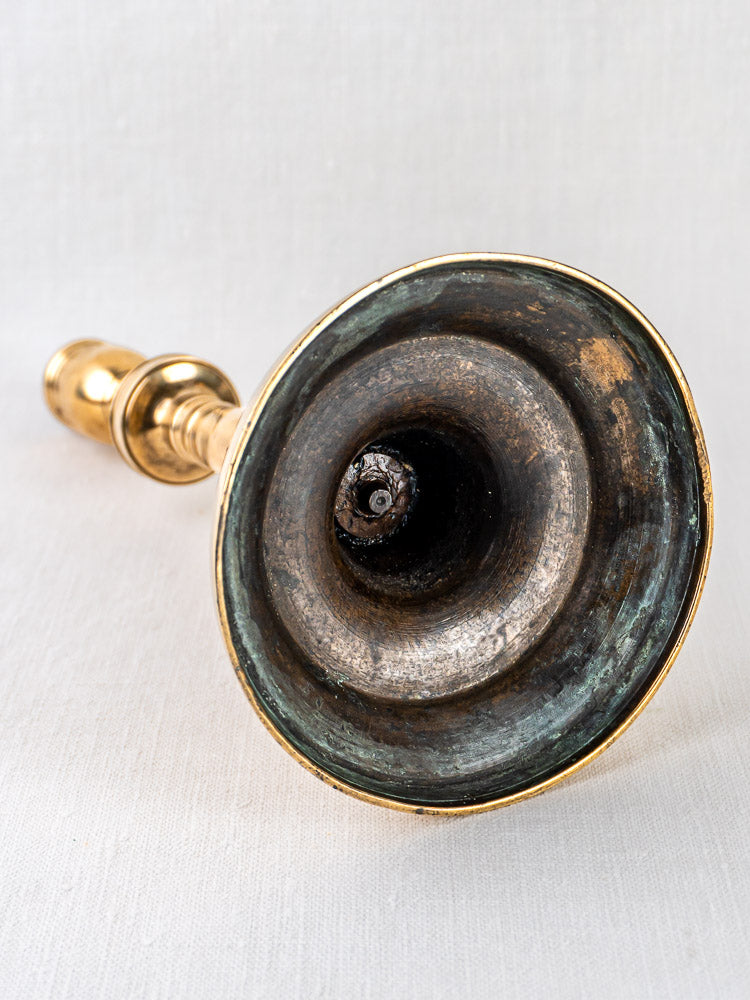 Close-up of a brass wind instrument bell with patina, echoing an antique French bronze bougeoir.