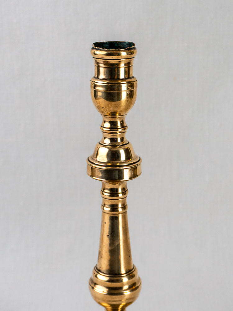 Antique French bronze turned baluster candlestick displayed upright on a simple light gray background.