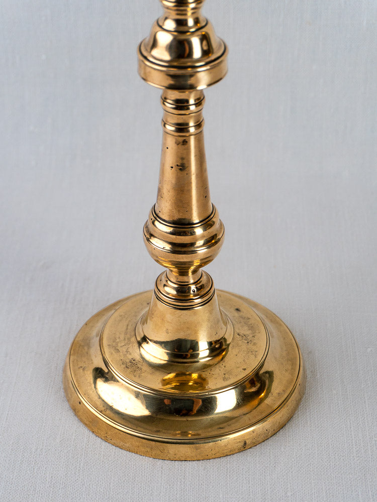 French bronze candlestick with polished finish and round base on a plain white background.
