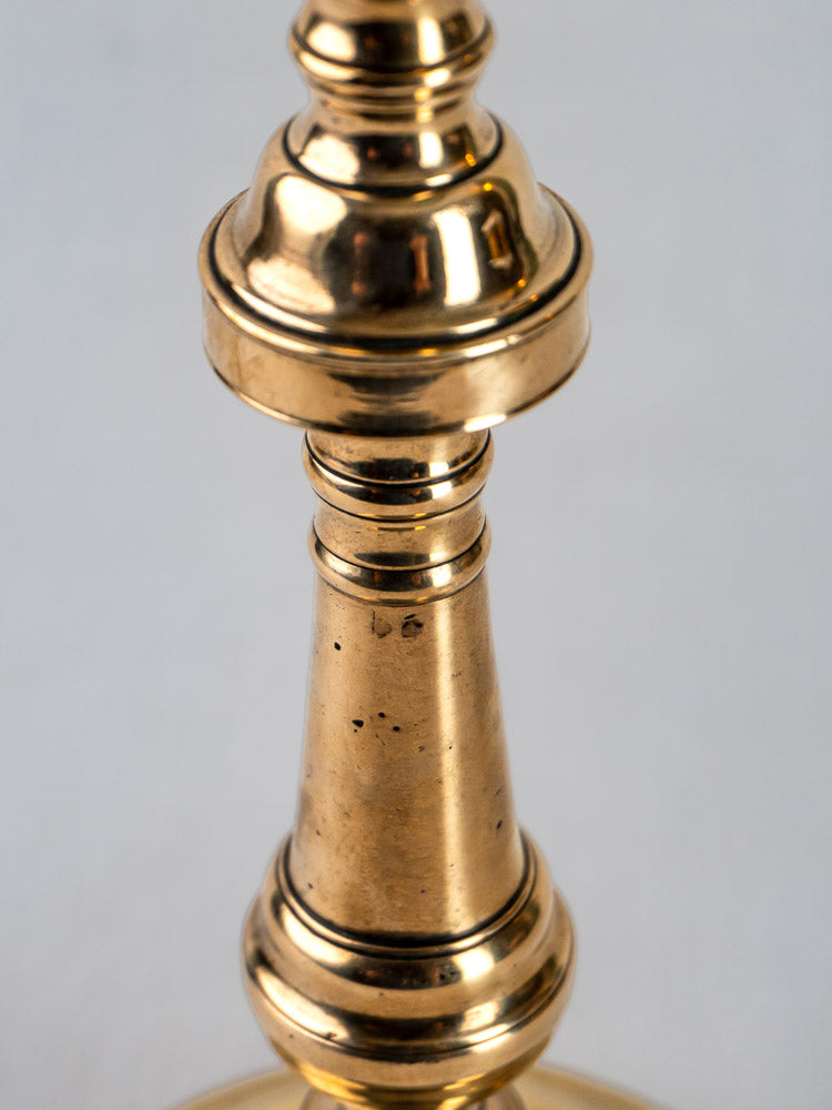 French antique bronze candlestick with turned baluster form and decorative rings on white background.