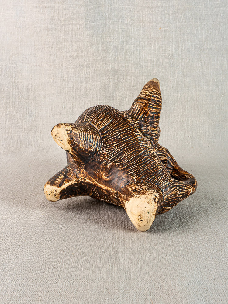 Vintage French bull ceramic zoomorphic pitcher, dark brown with tan accents, resting on neutral fabric background. Circa 1950.