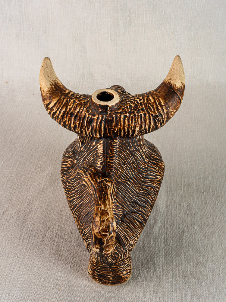 Ceramic vintage French bull zoomorphic pitcher, circa 1950, with horns and textured surface on neutral fabric background.