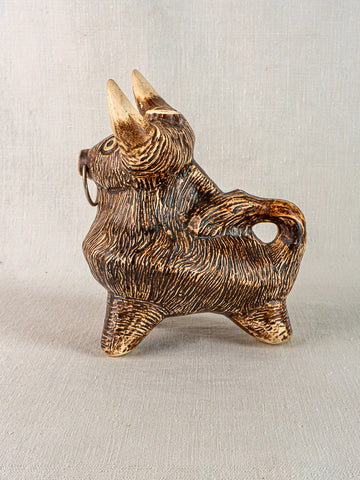 Ceramic French bull zoomorphic pitcher circa 1950, brown and cream glaze, horns, nose ring, back handle on neutral fabric.