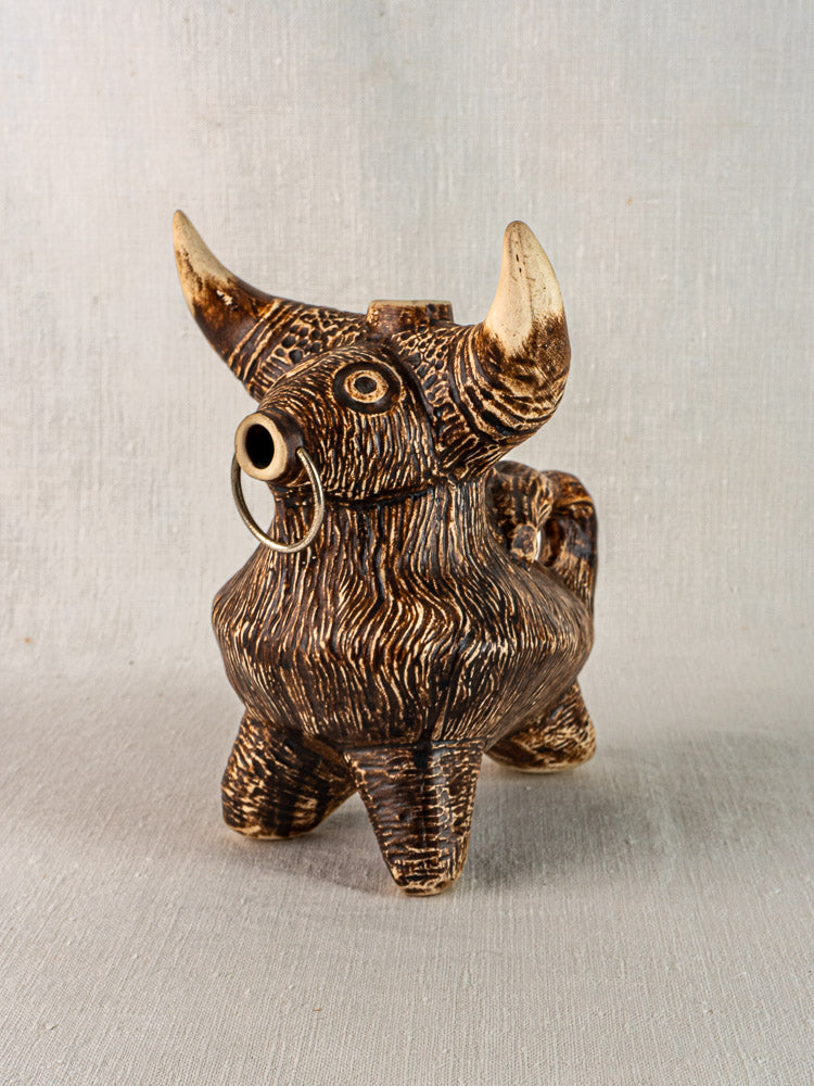 Vintage French ceramic bull pitcher, circa 1950, brown with tan horns and feet, on gray fabric surface.