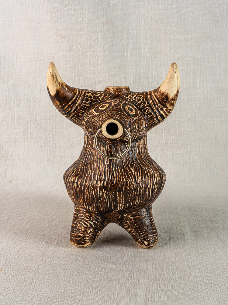 Vintage French bull zoomorphic ceramic pitcher, brown textured glaze, horned with nose ring, on neutral fabric background.