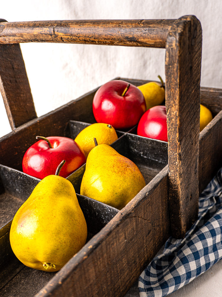 Antique French oak tool tote with hand-forged nails and six compartments on light fabric background.