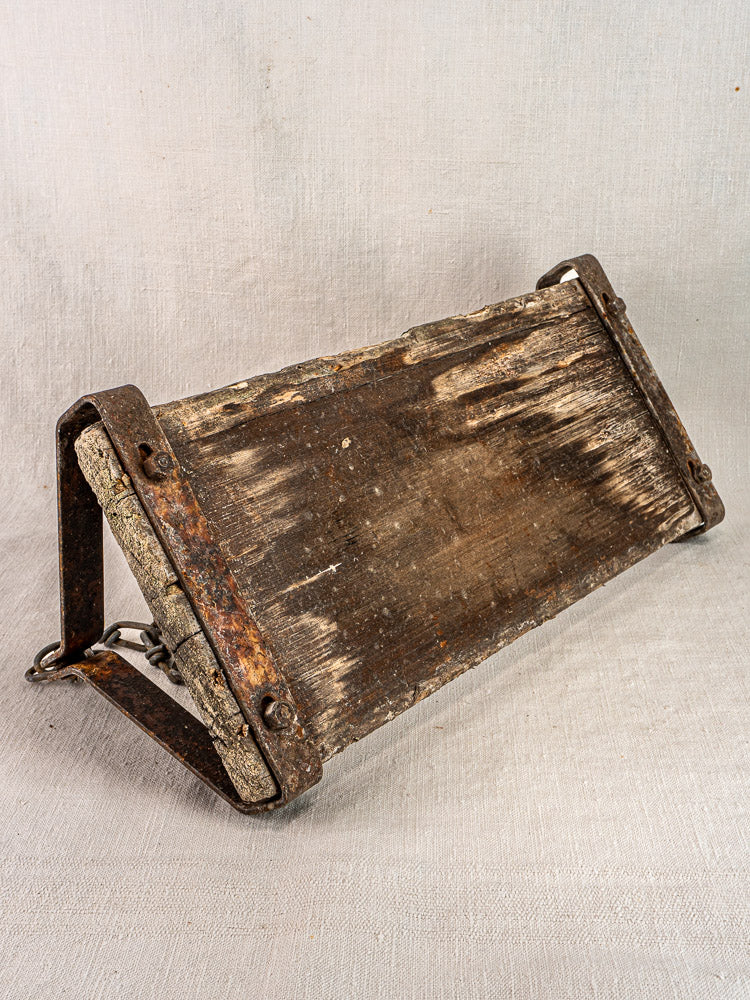 Antique French child’s swing, circa 1900, in weathered wood and iron on light textured surface.