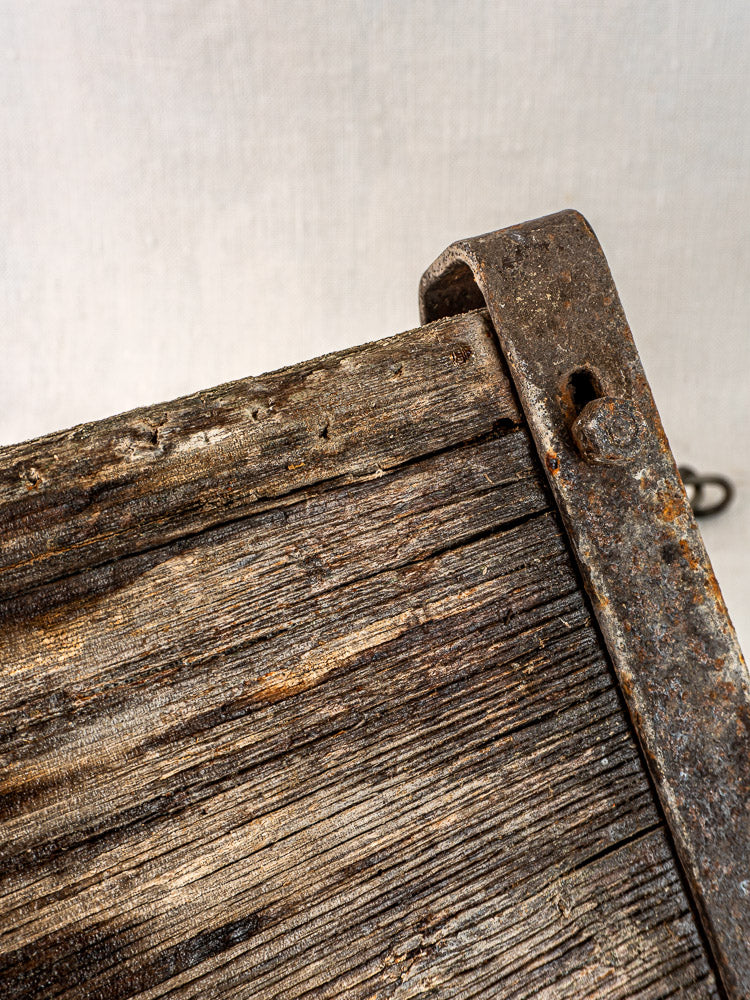 Antique French child’s swing with weathered wood and iron, aged textures, creamy fabric background.