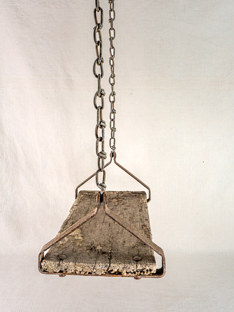 Antique French child’s swing, weathered wood and iron, circa 1900, on light fabric background.