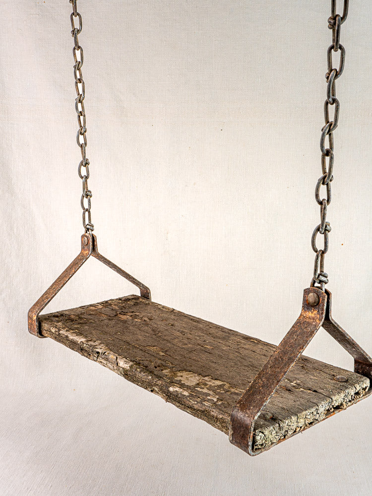 Antique French child’s swing in weathered wood and iron, circa 1900, with metal chains.