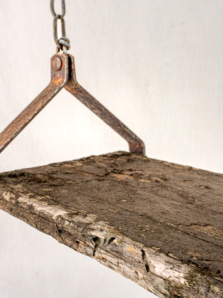 Antique French child’s swing, circa 1900, weathered wood with bark and iron chains, plain background.