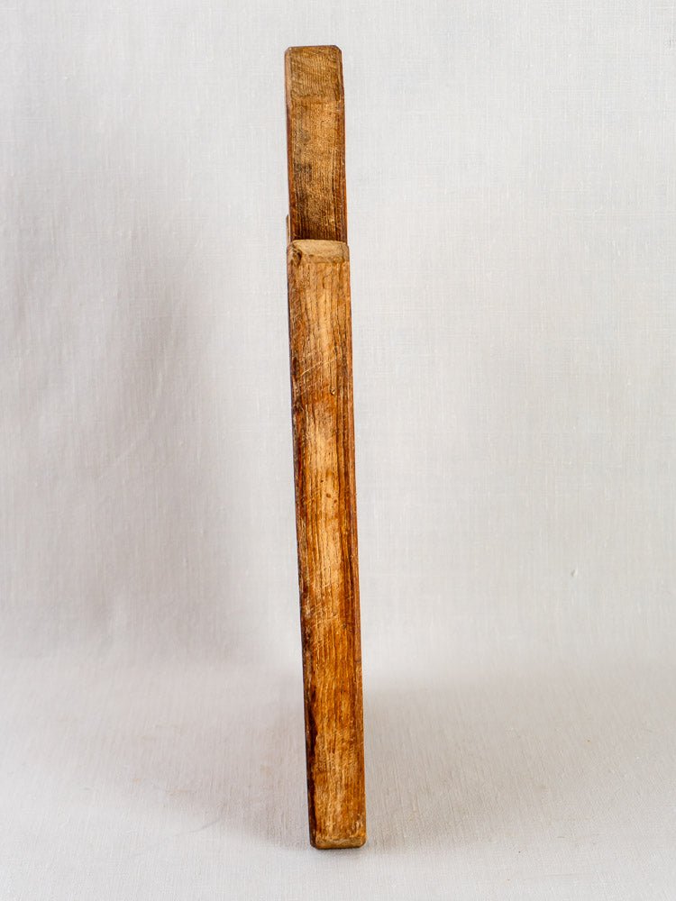 Antique French cutting board with faceted handle, 19th century, on light textured surface.