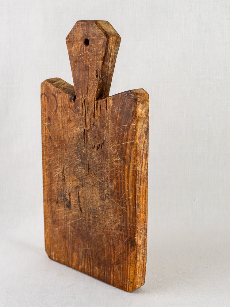 19th-century French antique cutting board with faceted handle and worn rectangular fruitwood form.