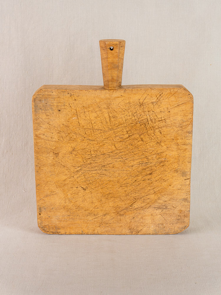 Antique French beech wood chopping board with six-sided handle, carved details, and patina on a light background.