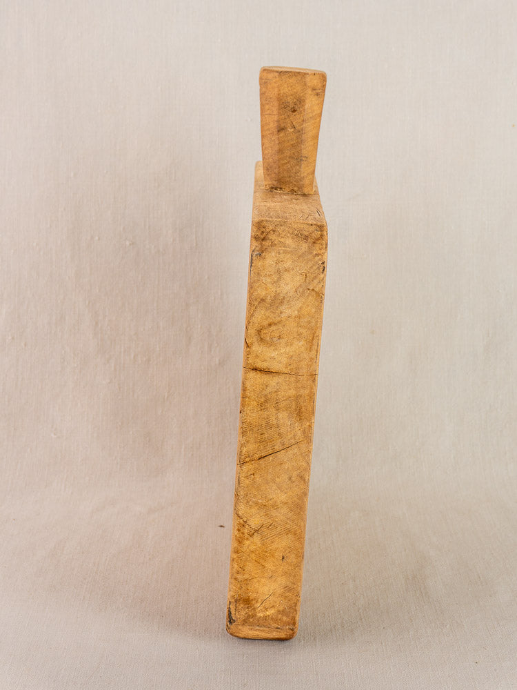 Antique French square chopping board with six-sided handle, upright, showing 19th-century wear against a light background.