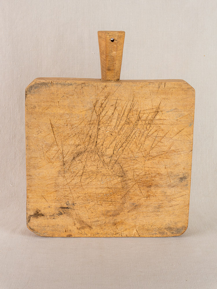 Antique French square chopping board with six-sided handle and knife marks, shown against a neutral background.