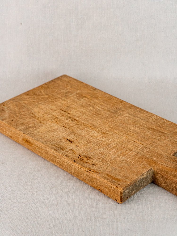 Antique French hardwood cutting board, 19th century, rectangular with corner notch on light surface.