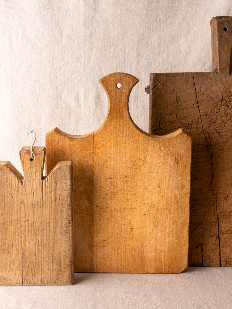 Antique French cutting board with fan handle, late 19th century, upright showing wood grain and aged patina.