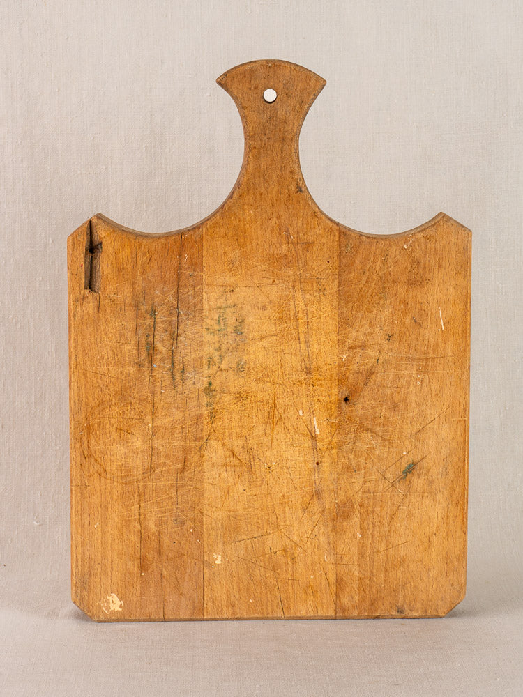 Antique French cutting board with fan handle, late 19th century, knife marks, dark stains, hole at top.