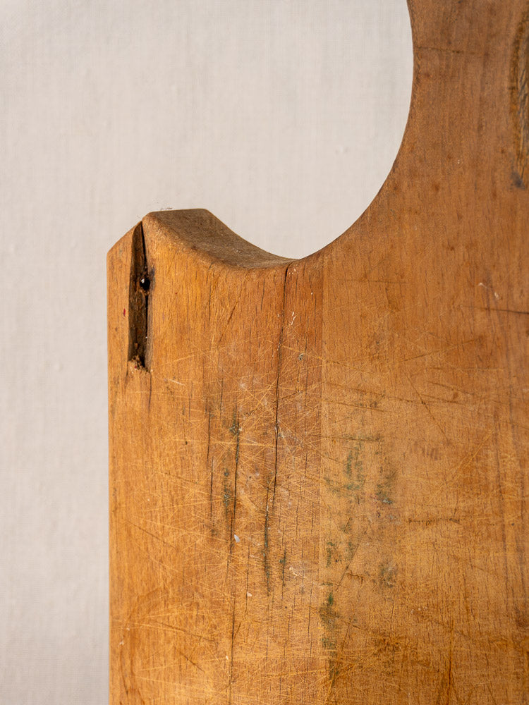Antique French cutting board with fan-shaped handle, late 19th century, scratches and chipped corner, neutral background.