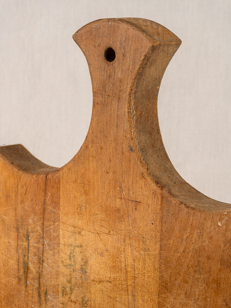 Antique French beech wood cutting board, fan handle, visible knife marks, late 19th century on neutral background.