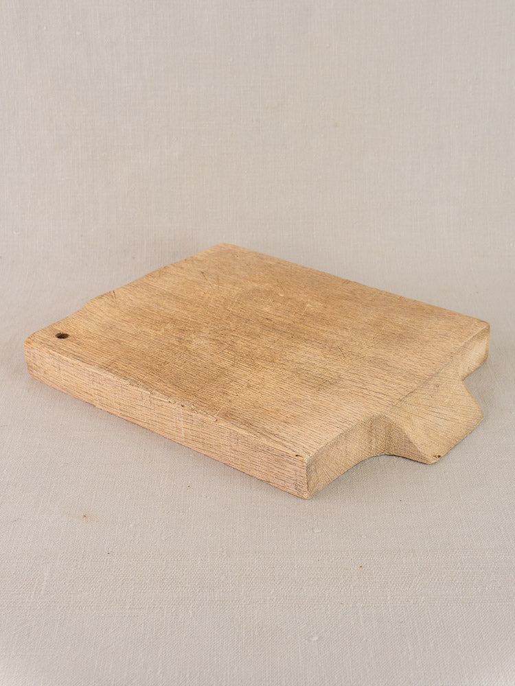 Antique French solid oak cutting board, circa 1900, with raised edge and groove, on a light surface.