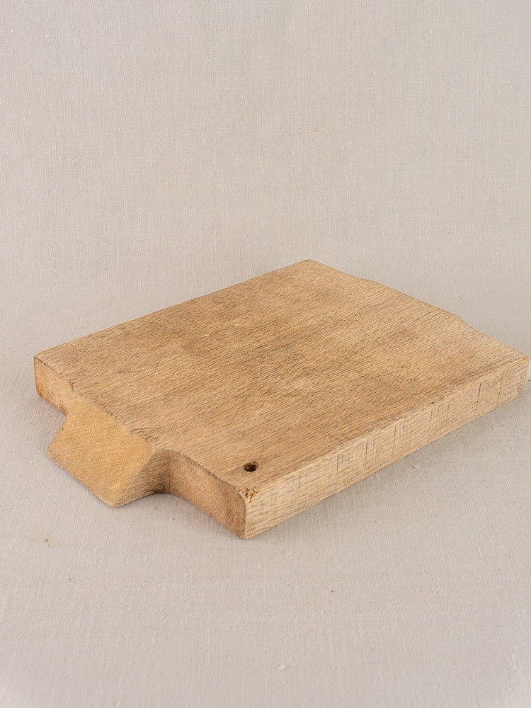 Antique French oak cutting board with sink-fit design, circa 1900, displayed on neutral fabric.
