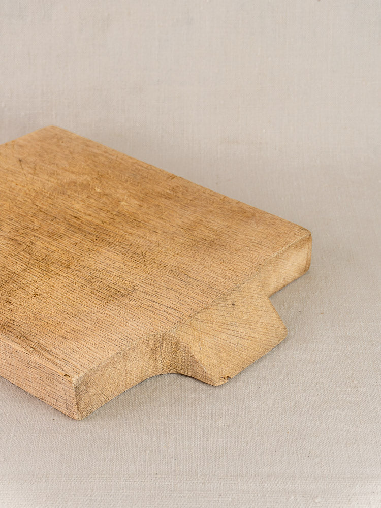 Antique French solid oak cutting board, sink-fit circa 1900, on light fabric surface.