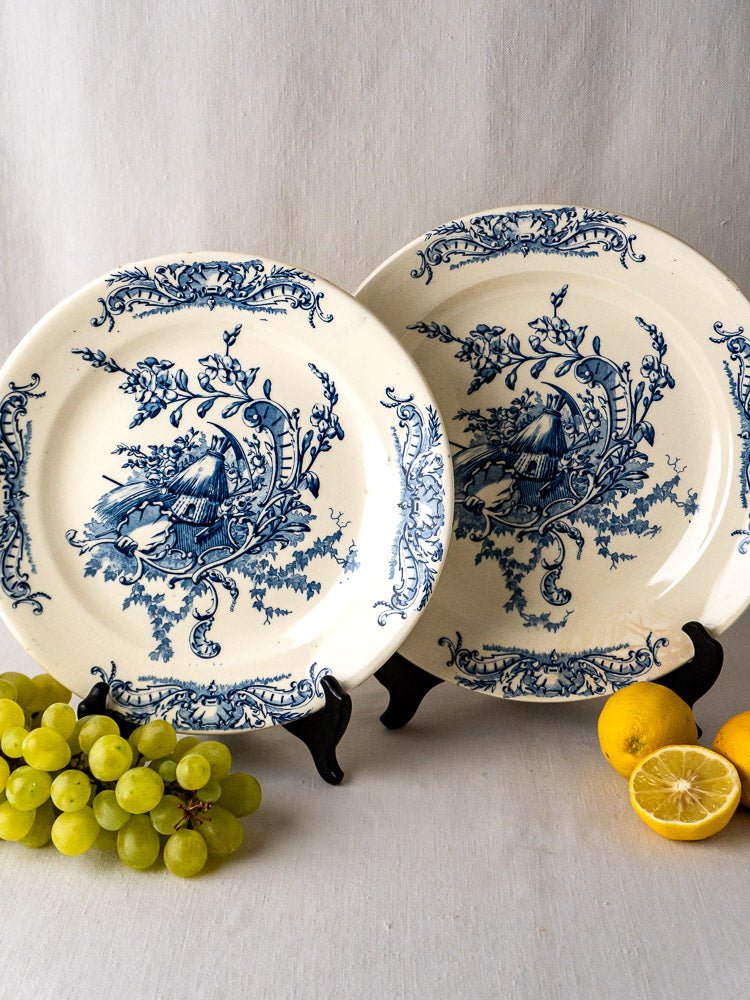 Pair of Clairefontaine Louis XV French Terre de Fer ceramic platters with blue floral cottage designs on black stands.