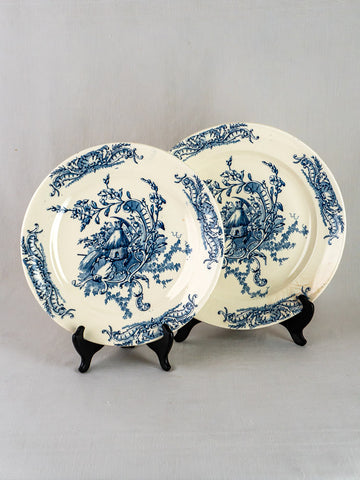 Pair of Clairefontaine Louis XV French Terre de Fer ceramic platters with blue floral cottage designs on black stands.