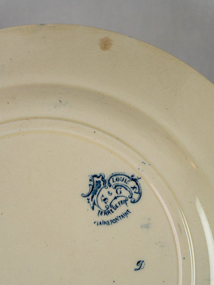 Underside of Clairefontaine Louis XV French serving platter with blue floral maker’s mark and glossy cream terre de fer finish.