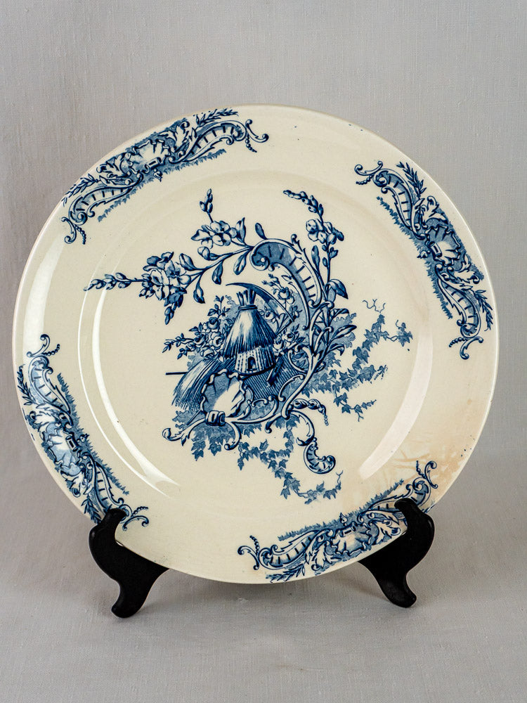 Pair of antique French Clairefontaine Louis XV Terre de Fer platters with blue floral and windmill motifs on black stand.