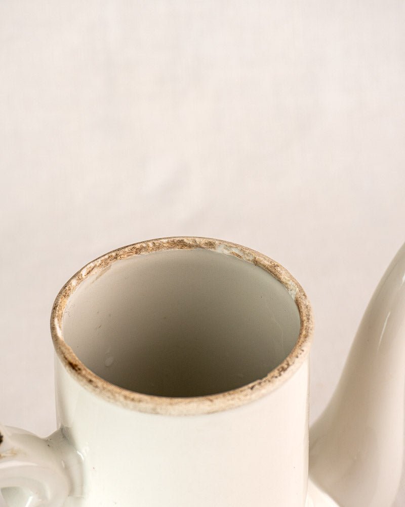 French Limoges Frugier Aluminite porcelain coffee pot with stained, chipped rim, plain light background.