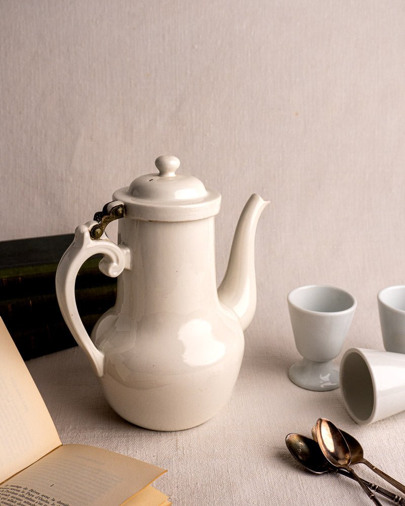 Early 20th century Frugier Limoges white porcelain coffee pot with lid, cups, spoons, and books.