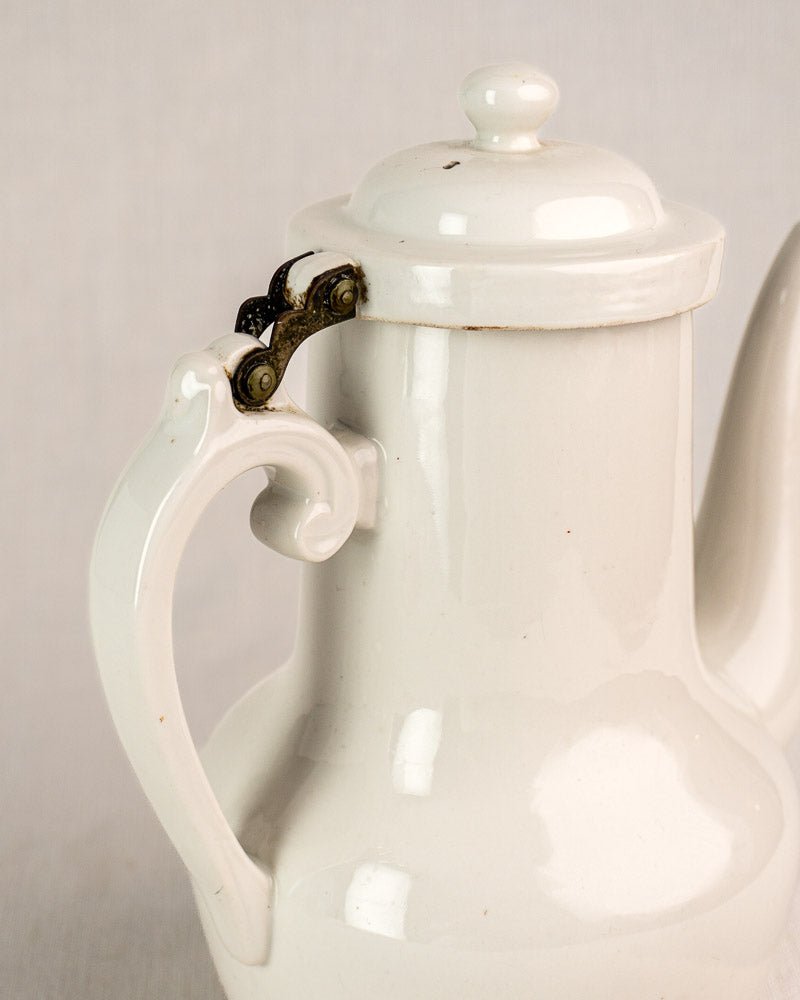 French Limoges aluminite porcelain coffee pot by Frugier with hinged lid and brass accents, plain background.