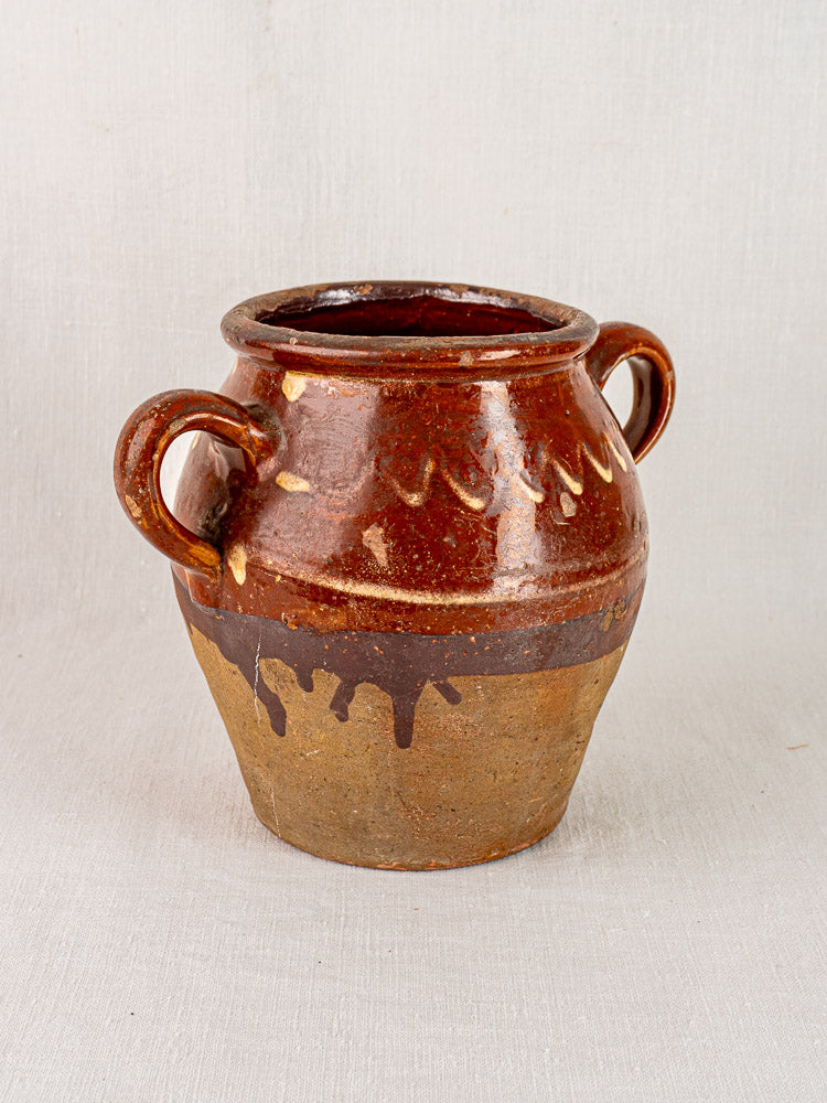 Mid-19th century French confit pot with brown glaze, yellow slipwork, side handles; glossy and matte finish on light surface.