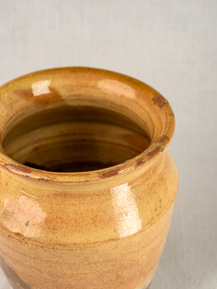 Late 19th century French confit pot with yellow glazed terracotta, wide mouth, brown streaks on gray background.