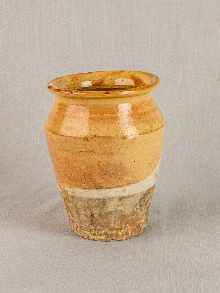 Late 19th-century French confit pot with yellow glaze, wide mouth, textured base, glossy top on gray background.
