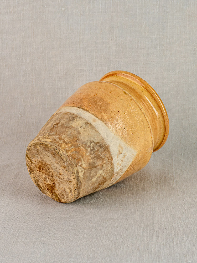 Late 19th c. French yellow-glazed confit pot, terracotta, weathered base, smooth glazed top, on gray background.